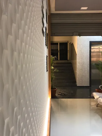 A 3D textured wall panel adds another layer of visual interest in the clinic's hallway, playing with light and shadow.