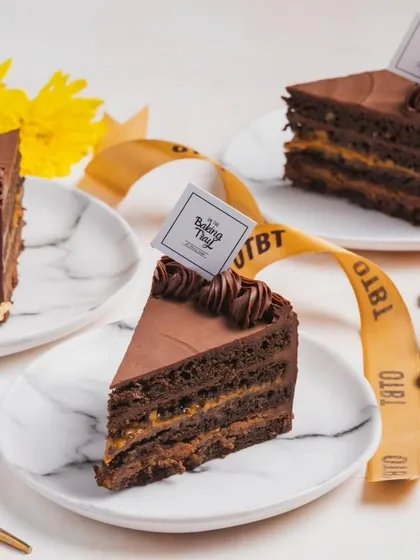 A slice of my Billionaire’s Cake is pure indulgence. It features five layers of rich 55% chocolate ganache, caramel sea salt, hazelnut praline, and chocolate mousse.