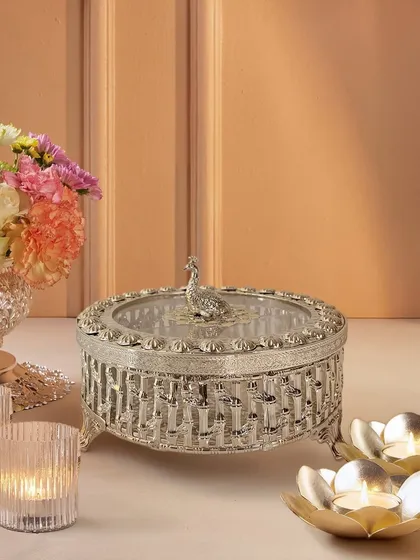 This silver-plated dry fruit box is a study in intricate detail. From the woven-style engraving to the regal peacock handle, it is a piece that is as beautiful to display as it is useful to serve from.