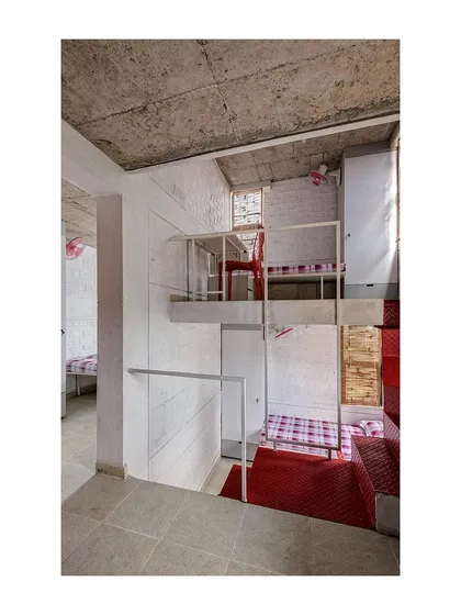 This view shows the connection between the lower sleeping area and the upper study loft in the student housing unit. The design provides distinct zones for different activities within a compact space.