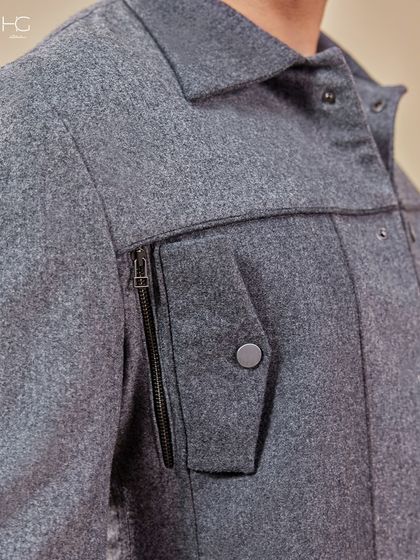 This close-up of the grey shacket highlights the zippered pocket detail, adding a touch of functional, urban style to the understated monochrome piece.