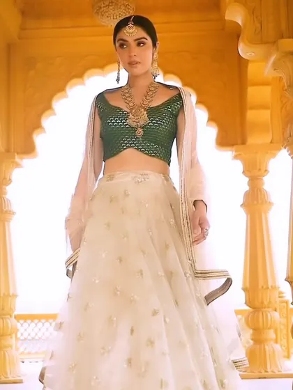 A full-length view of the temple jewellery look. The styling, with an elegant off-white and gold lehenga and a contrasting green blouse, creates a sophisticated and graceful silhouette for the modern bride.