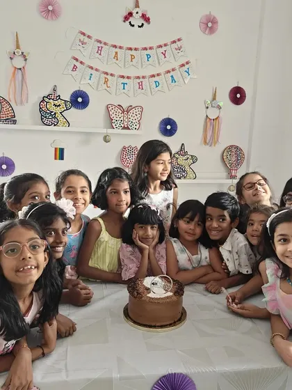 A magical unicorn-themed birthday party! The girls are all smiles as they gather around the cake after a creative session.