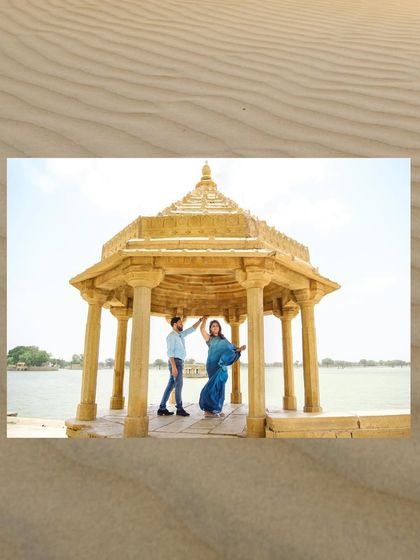 A lovely portrait of the couple under a traditional stone chhatri by the lake in Jaisalmer. The sand-textured border adds a thematic touch.