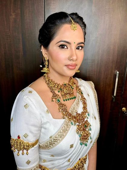A close-up of the pooja look, showing the soft contouring and the warm, earthy tones on her eyes that complement the temple jewelry.