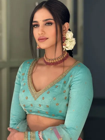 A model wearing a light blue, full-sleeved crop top with delicate embroidery. This versatile piece can be paired with a lehenga, saree, or pants for a modern ethnic look.