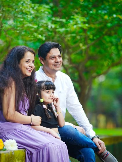 A relaxed family portrait, with the family of three sitting together on a park bench, enjoying the peaceful outdoor atmosphere.