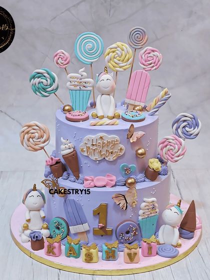 A magical two-tier Candyland unicorn cake for a first birthday. This large pineapple cake is a fantasy of pastel purples and pinks, covered in fondant unicorns, lollipops, and ice cream cones.
