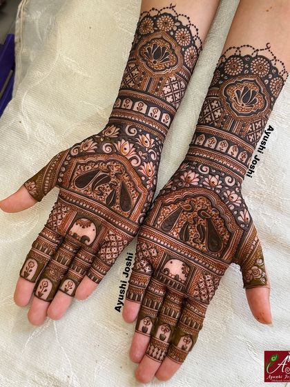A lovely peacock designer mehendi for the bride's sister, featuring elephants on the fingers and lotuses on the wrist.