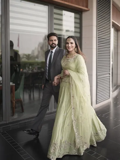 A candid walking shot of the couple. Harman's makeup looks effortless and chic, perfect for a daytime engagement event.