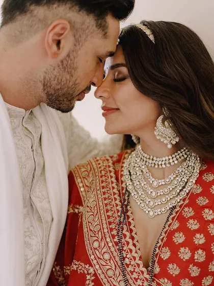 A duplicate of image 16, this intimate close-up of the couple highlights the bride's magnificent layered Tyaani Jewellery necklace and statement earrings, which were the centerpiece of her wedding look.