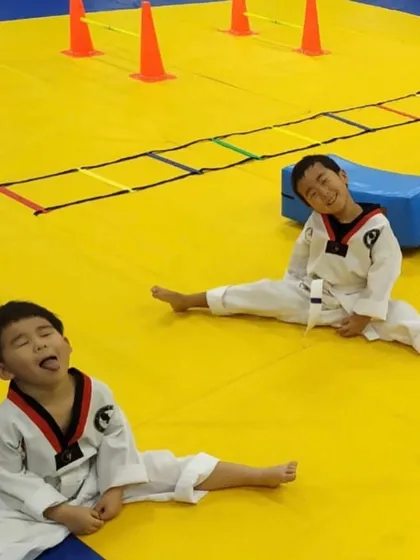 Training is serious, but it's also fun. These happy faces show our youngest students enjoying a post-training stretch, building flexibility and camaraderie after a challenging session on the mats.