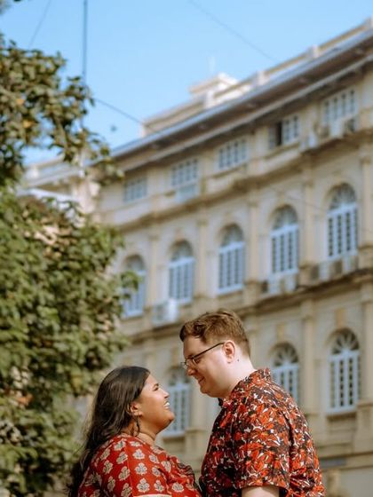 A wide shot of a couple with a grand heritage building in the background, perfect for telling a story of love in the city of Mumbai.