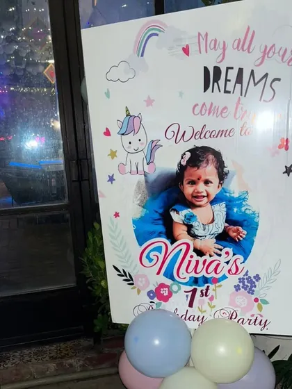 A personalized welcome board for a unicorn-themed first birthday party, featuring a cute unicorn graphic and a photo of the birthday girl.