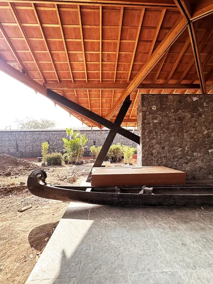 A detail from the Alibaug residence, where a traditional wooden boat form is integrated into the veranda. This element adds a layer of local culture and artistry to the architectural composition.