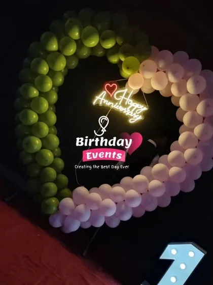 A unique take on the classic arch, this heart-shaped balloon frame is perfect for anniversaries. Made with green and pink balloons, it surrounds a "Happy Anniversary" neon sign for a truly romantic statement.