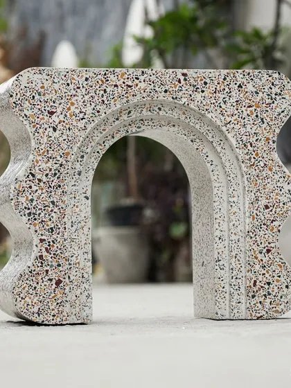This view showcases the arched structure of the custom terrazzo bookshelf. The piece plays with positive and negative space, creating a sense of lightness despite being made from solid terrazzo.