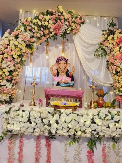 This is a complete and luxurious home Ganpati setup, featuring a grand floral arch and an abundance of flowers to create a truly special display.