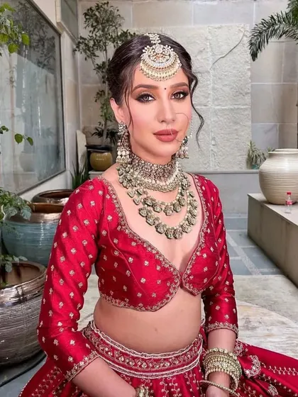 A radiant bride in a classic red lehenga. I styled this with heavy, layered Kundan jewelry to create a look of timeless opulence.