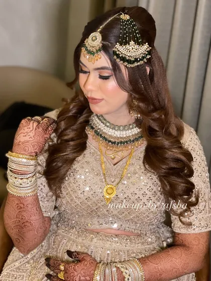 This bride's beige and gold lehenga was paired with contrasting green jewellery. I created a soft, neutral makeup look with a nude-brown lip to tie it all together.