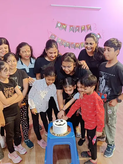 The kids and moms coming together to cut the Halloween cake. It's a family-friendly space.