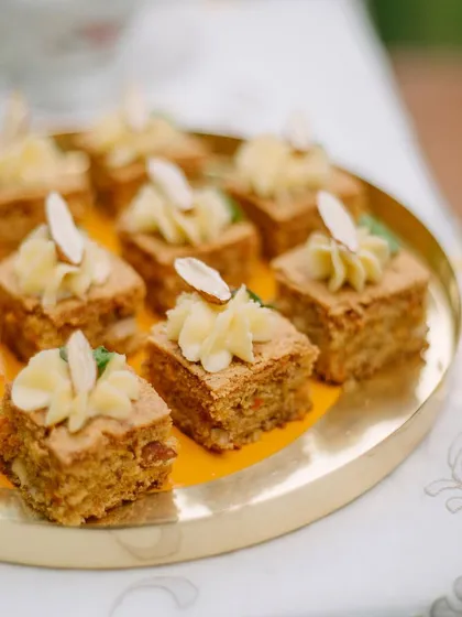 Grandma's carrot cake, served as bite-sized portions for a party. Each square is topped with a swirl of our signature mascarpone frosting.