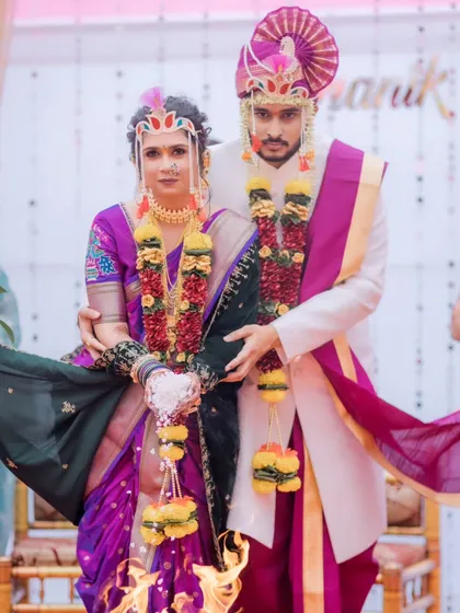 A playful moment during the wedding ceremony. The bride's Nauvari saree and traditional accessories are perfectly in place.