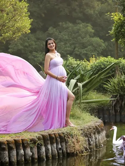 A princess moment. Standing by the water with swans gliding by, this mom-to-be in her flowing pink gown looks like she's stepped out of a fairytale.