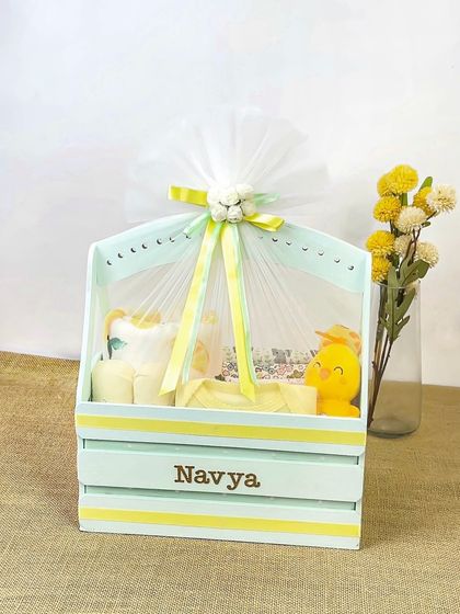 A personalized baby gift crate for 'Navya'. The photo captures the delicate wrapping and ribbon details, adding to the premium feel of the gift.