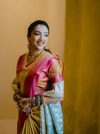 A quiet, happy moment before the ceremony. Her makeup features soft, blended shades that enhance her features without overpowering them, ensuring she looks timeless in her beautiful silk saree.