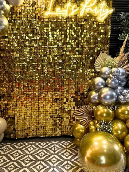 The lower corner of the gold party setup, showing how the balloon clusters ground the installation, with dried floral elements adding a touch of boho chic.