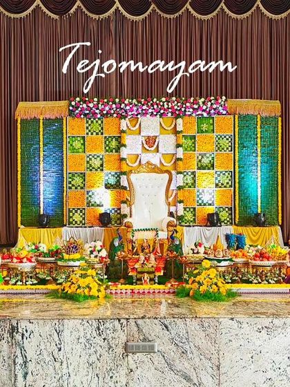 A grand baby shower setup with a marigold checkerboard backdrop and two large elephant statues, symbolizing strength and good fortune.