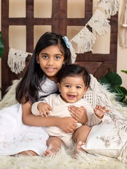 A big sister gives her baby brother a warm hug in our cozy, bohemian-style setup. The natural textures and colors create a calm and loving scene.