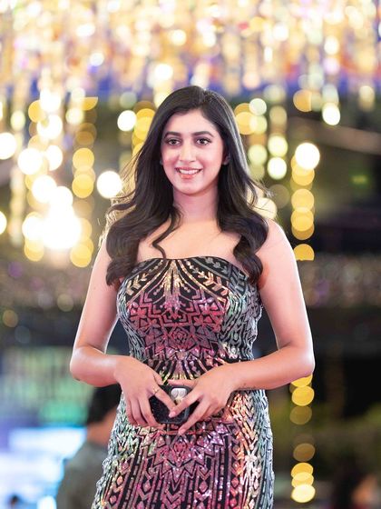 A guest smiling for the camera, her sequined dress shimmering under the event lights.