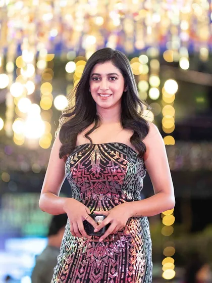 A guest smiling for the camera, her sequined dress shimmering under the event lights.