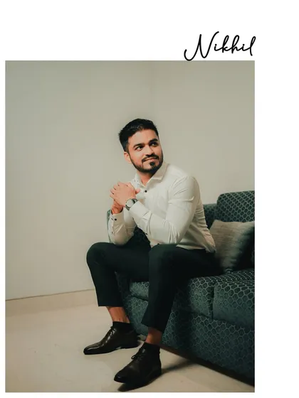 A relaxed, candid portrait of the groom seated on a couch. This natural pose captures his personality in a comfortable setting.