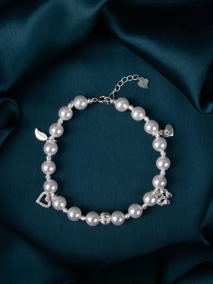 A pearl bracelet with multiple silver charms, including a heart and a wing.