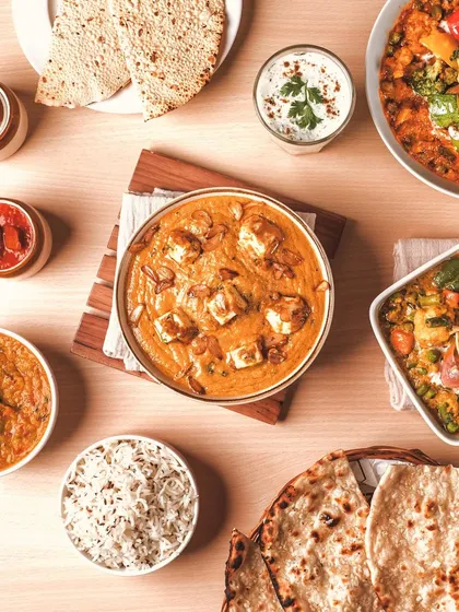 A vibrant top-down view of a classic Indian meal. My food styling focuses on arranging dishes like this paneer curry, naan, and rice to create a full, inviting picture that’s perfect for menus and social media.