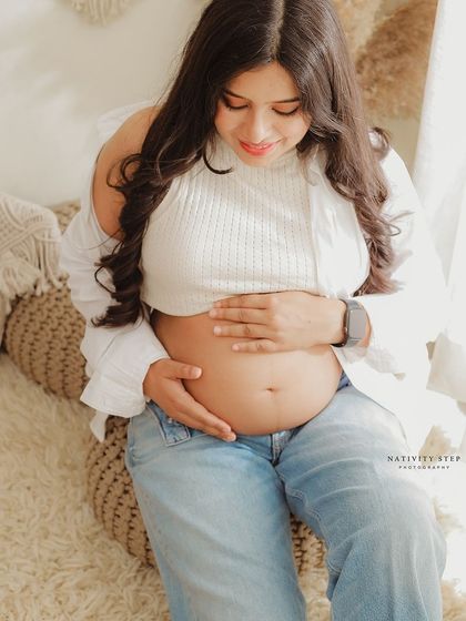 A close-up on the baby bump in a casual, lifestyle setting. This shot celebrates the natural beauty of the pregnant form.