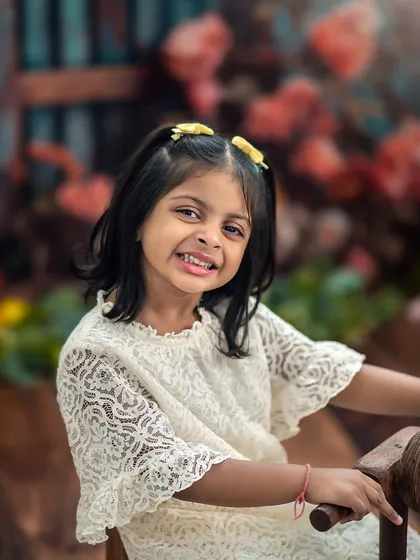 A cheeky grin from this big sister. Her personality shines in this close-up from our floral garden sibling shoot.