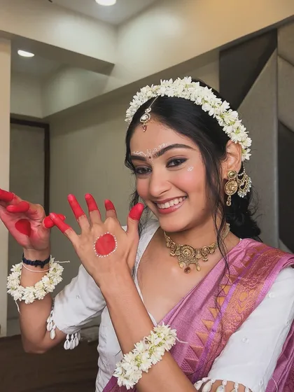 A joyful expression from my client in her Radha-inspired look, showing the traditional alta design on her hands and the fresh flower jewelry.