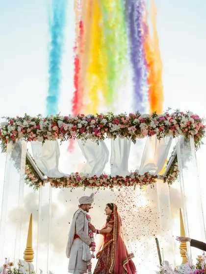 Nothing hits different than a Goa wedding. We created this magical Varmala moment with a floral arch against the sky, using colored smoke to paint the clouds and make the moment truly unforgettable for the couple.