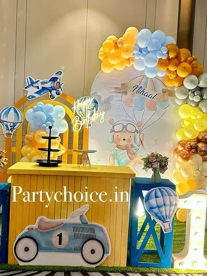 A transportation-themed first birthday combining hot air balloons, airplanes, and a vintage car. The bright yellow and blue color scheme is perfect for a little boy's party.
