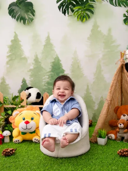 The jungle just got a whole lot cuter. This happy baby is surrounded by friendly stuffed animals in our vibrant jungle-themed setup.