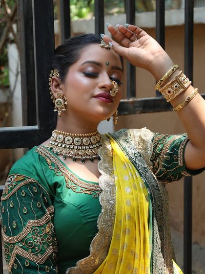 An elegant pose highlighting the detailed embroidery on the green blouse.