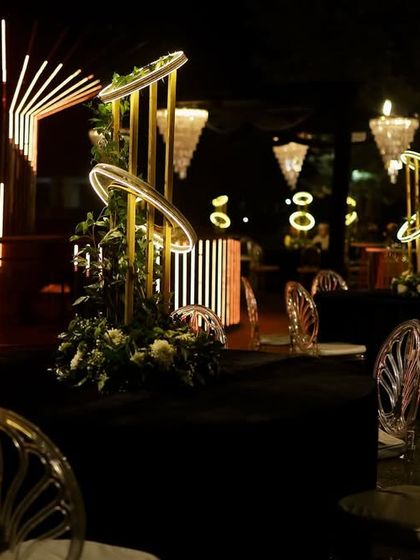 A wide view of the Sangeet space, showing the interplay of the modern LED bar, glowing centerpieces, and dramatic chandeliers.