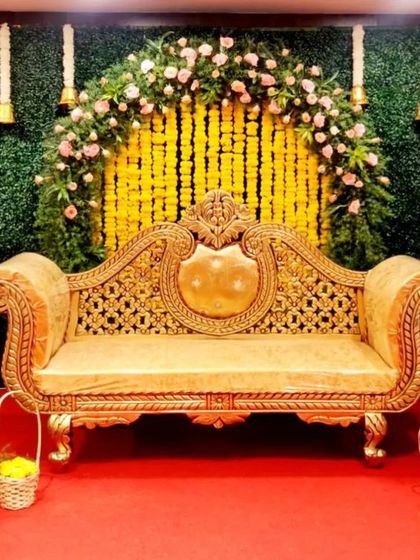 I designed this engagement stage with a mix of traditional and rustic elements. The backdrop features a curtain of marigold strings inside a floral arch, with lanterns and small baskets of flowers adding a charming touch.