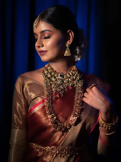 A dramatic and artistic shot of a model in a traditional muhurtham look, with beautiful lighting that highlights her features and the rich colors of her attire.