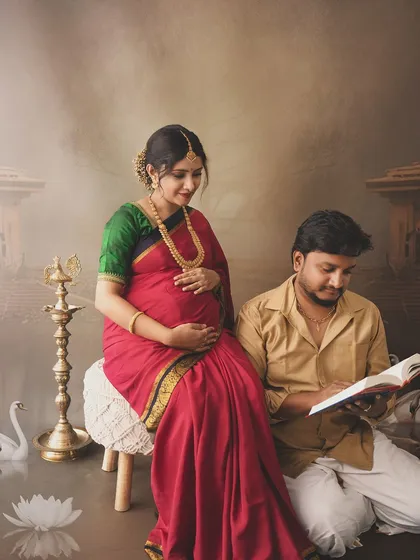 A serene scene of an expecting couple in a traditional setting, with the father-to-be reading beside his wife, creating a peaceful and scholarly atmosphere.