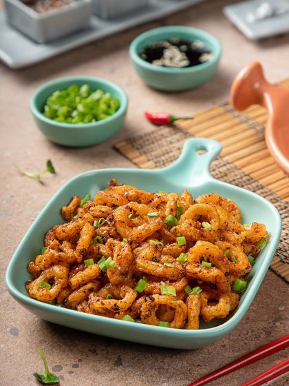 Crispy fried calamari rings in a contemporary bowl, photographed for YouMee. The bright colors of the dish and bowl create a playful and appetizing image.